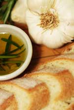 a plate of garlic, bread, rosemary and olive oil
